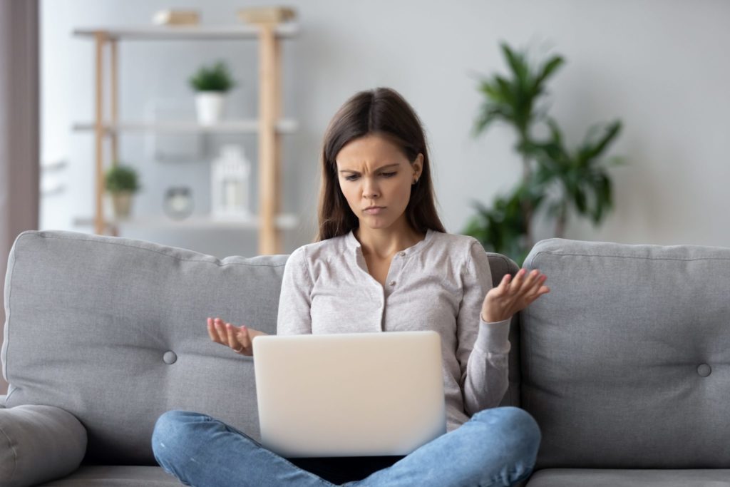 Woman looking at laptop frustrated there is no signal.
